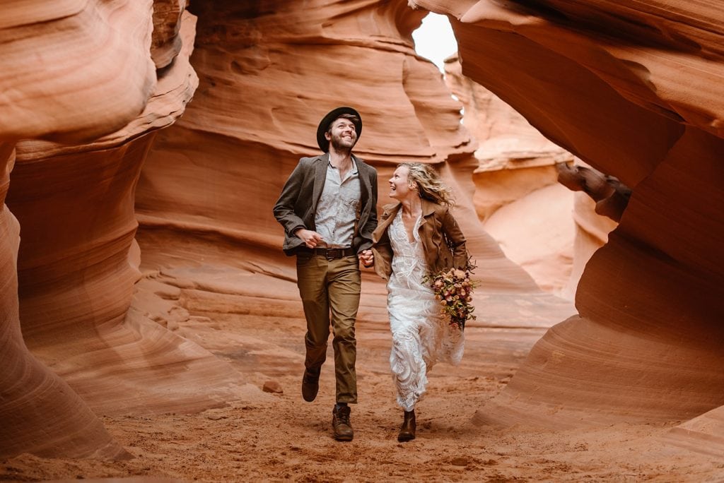 Happy wedding couple runs through slot canyon at their elopement