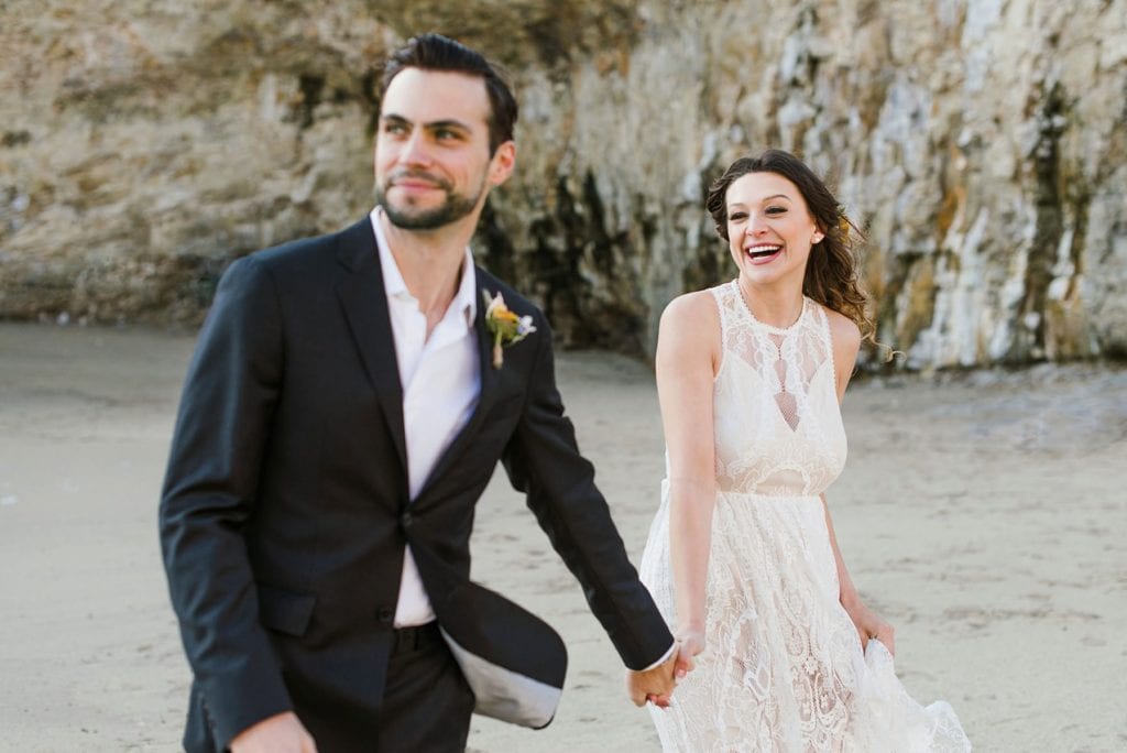 Adventurous couple runs on California beach at their elopement