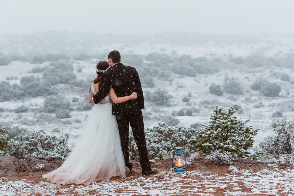 Couple with arms around each other looking out into the snowy desert