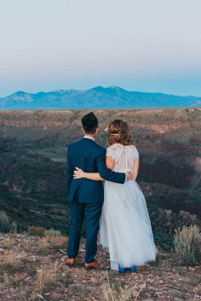 Wedding couple looks out over the Rio Grande Gorge to the mountains of Taos.