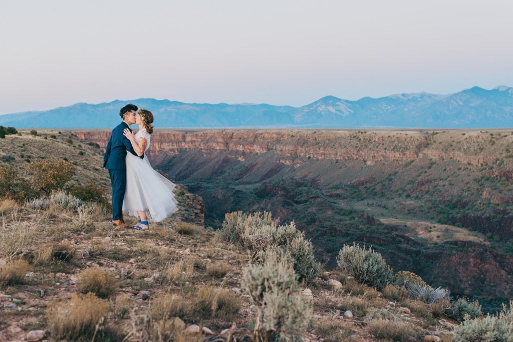Same-sex couple kisses on the edge of the Rio Grande Gorge at sunset