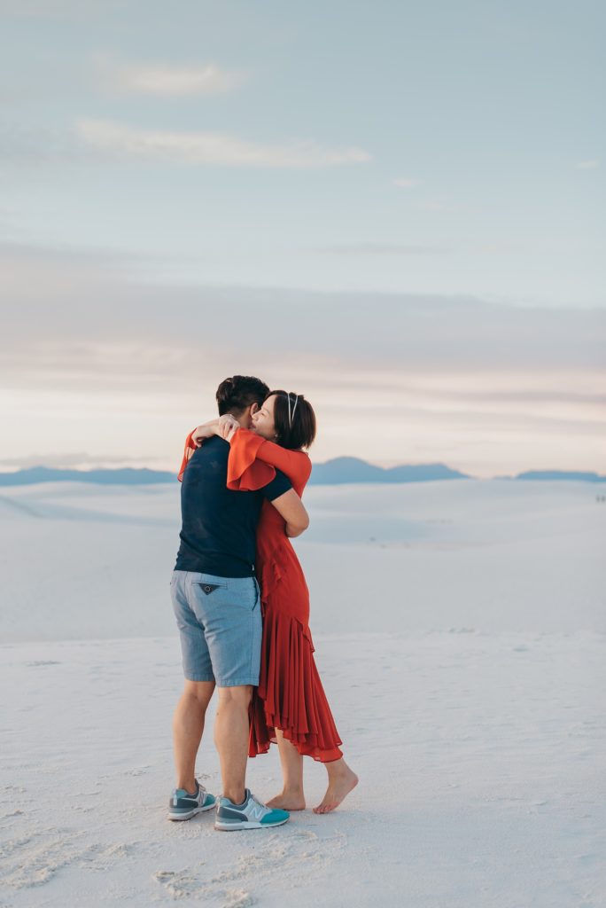 Couple hugs on white gypsum sand dunes for their engagement photos
