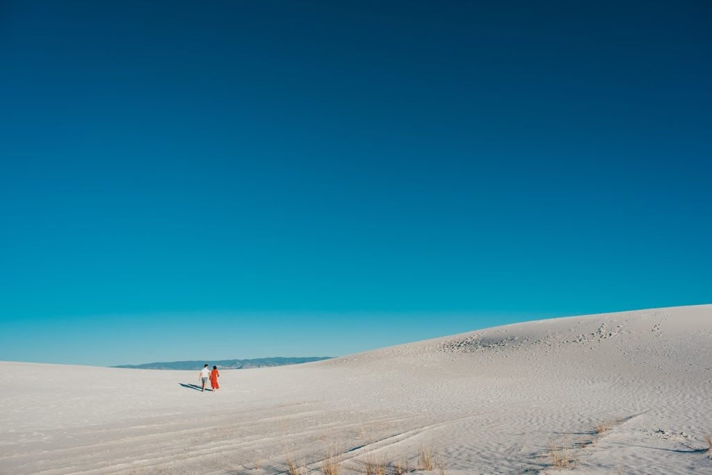 Couple in the distance walks through white sand dunes in New Mexico