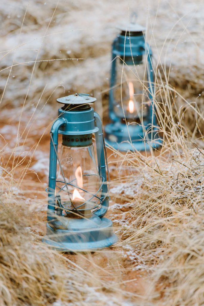 Blue kerosene lanterns sit on the ground as elopement ceremony decorations