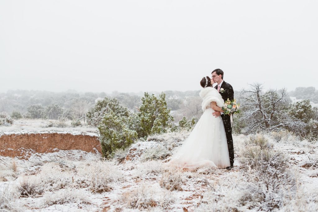 Bride and groom kiss in the desert snow of New Mexico